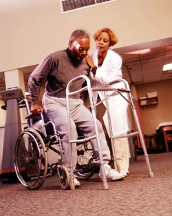 A caregiver helping a man out of a wheelchair.